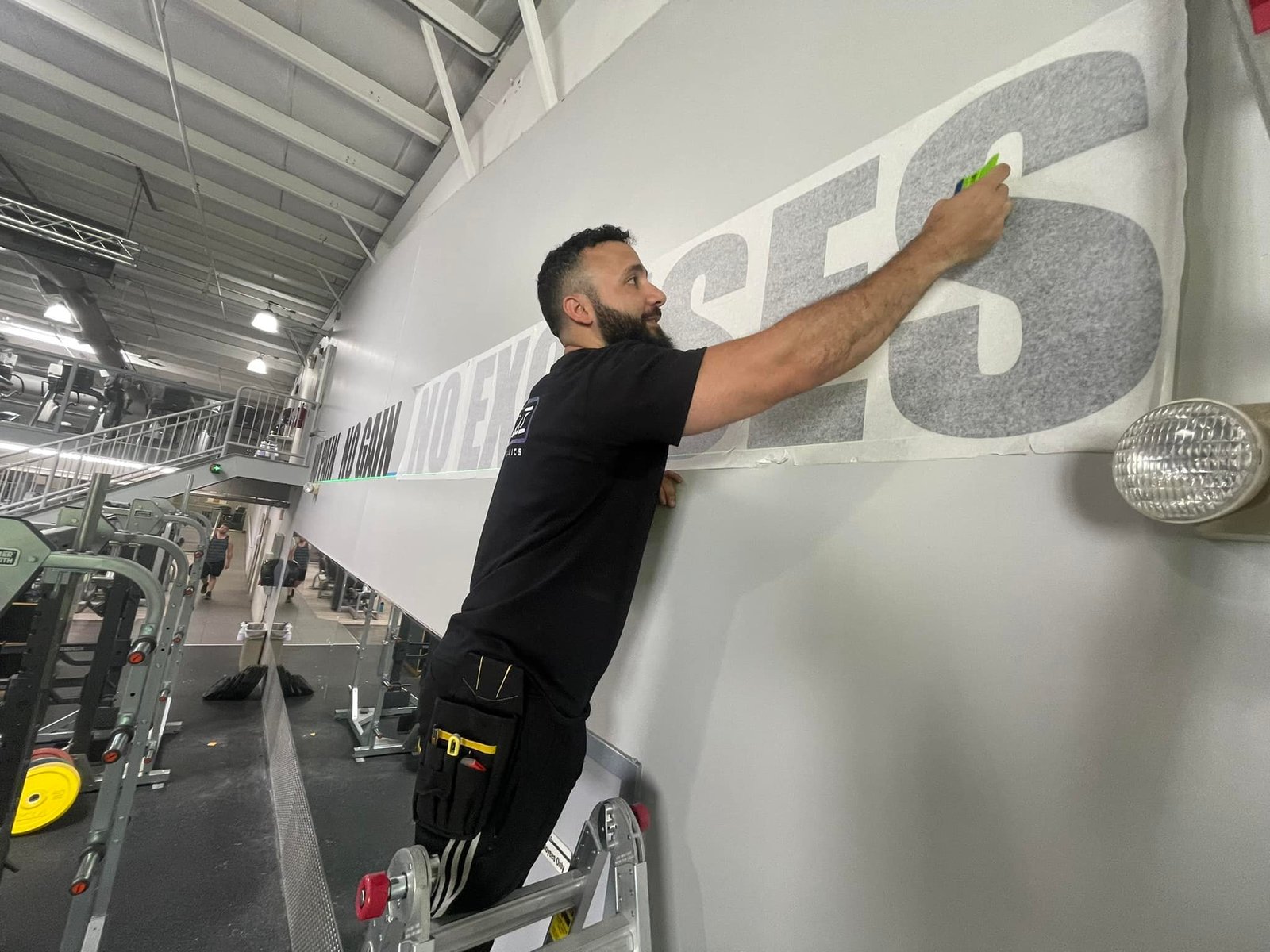 Installing black wall lettering at The Workout Club in Londonderry, NH