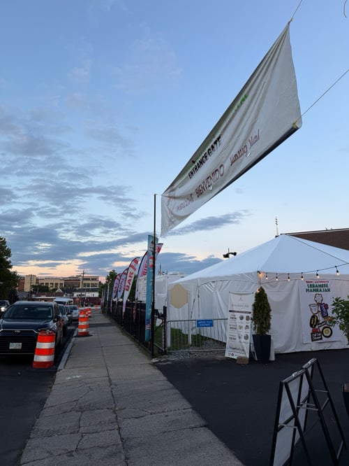 Entrance gate of Saint Anthony's Lebanese Mahrajan in Lawrence, MA, with a welcome banner, pole banners and feather flags