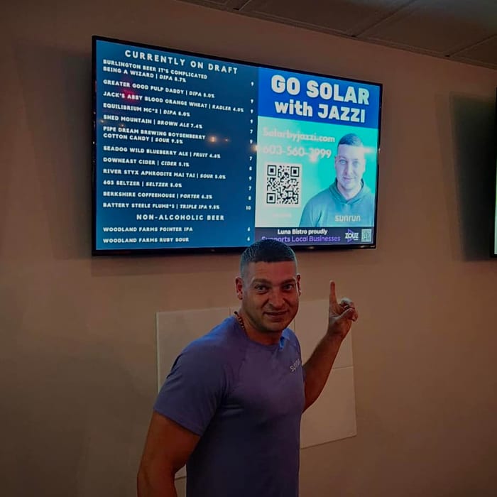 Jason of Solar by Jazzi pointing at his ad on a Pixel Billboards screen