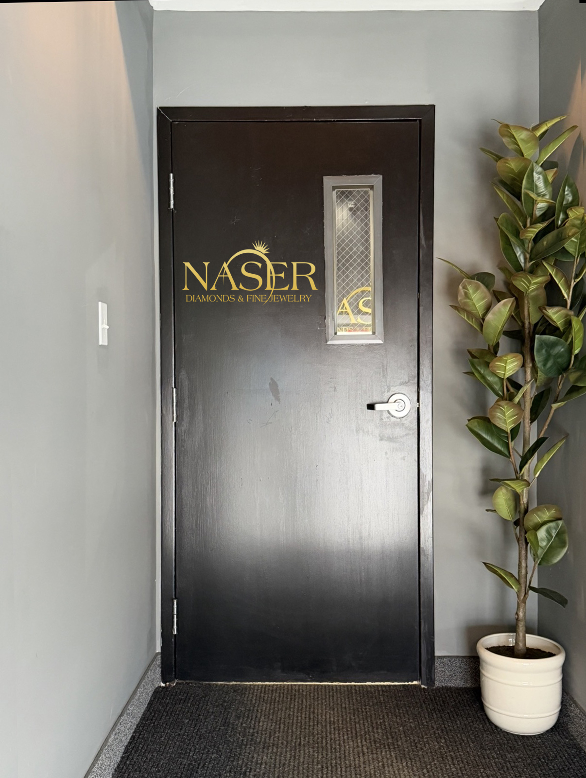 Gold Naser vinyl lettering on a dark office door